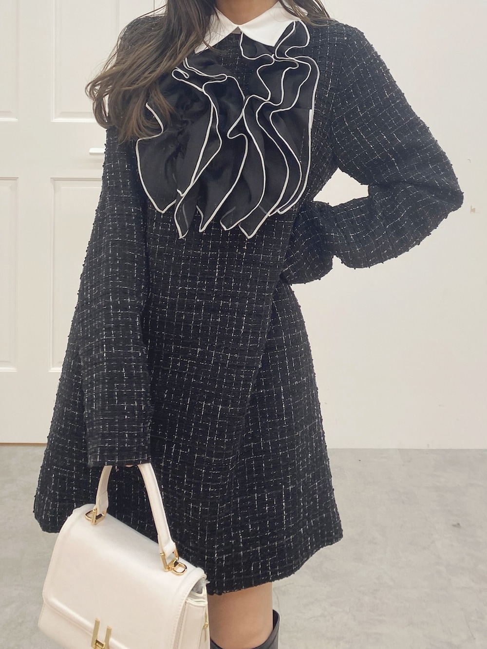 ブラック系のブーツ、ホワイト系のハンドバッグ、ブラック系のワンピースを着用したレディースの秋コーディネートの5枚目の写真