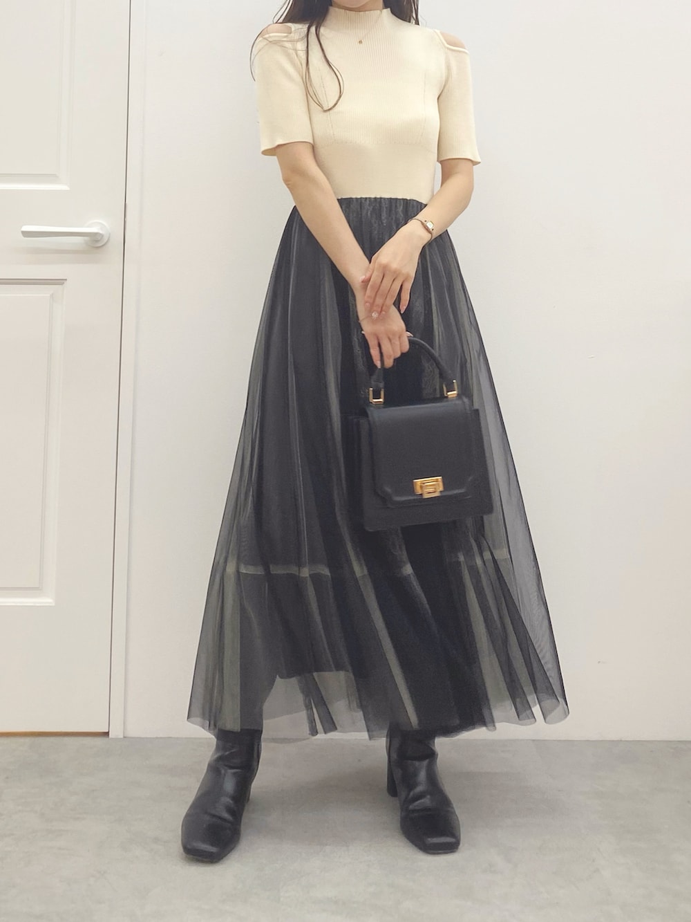 ブラック系のハンドバッグ、ブラック系のブーツ、ホワイト系のワンピースを着用したレディースの夏コーディネートの3枚目の写真