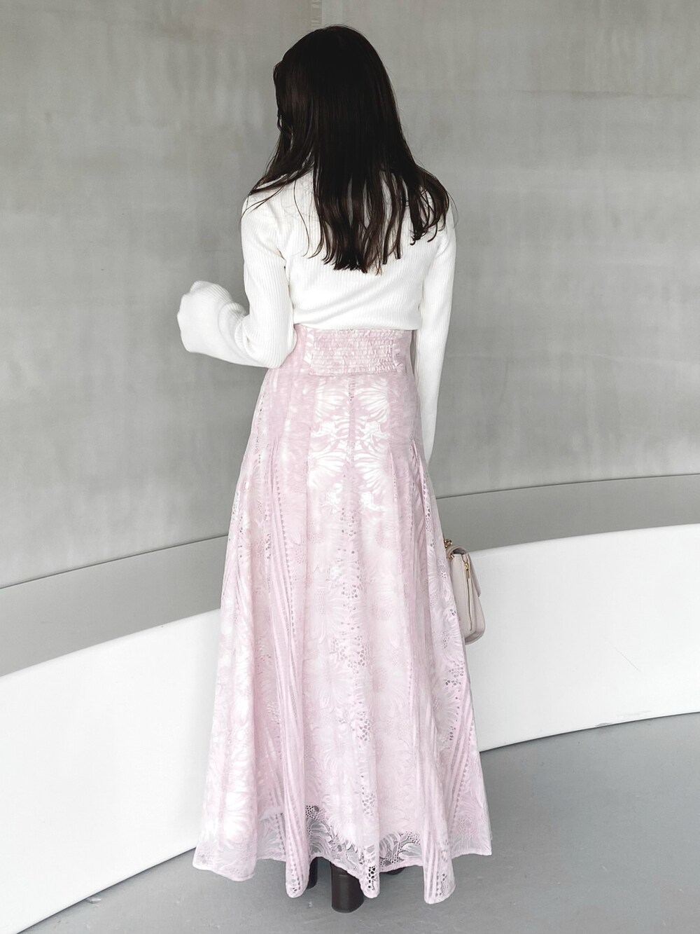 ピンク系のハンドバッグ、ピンク系のスカート、ホワイト系のニット/セーターを着用したレディースの冬コーディネートの6枚目の写真