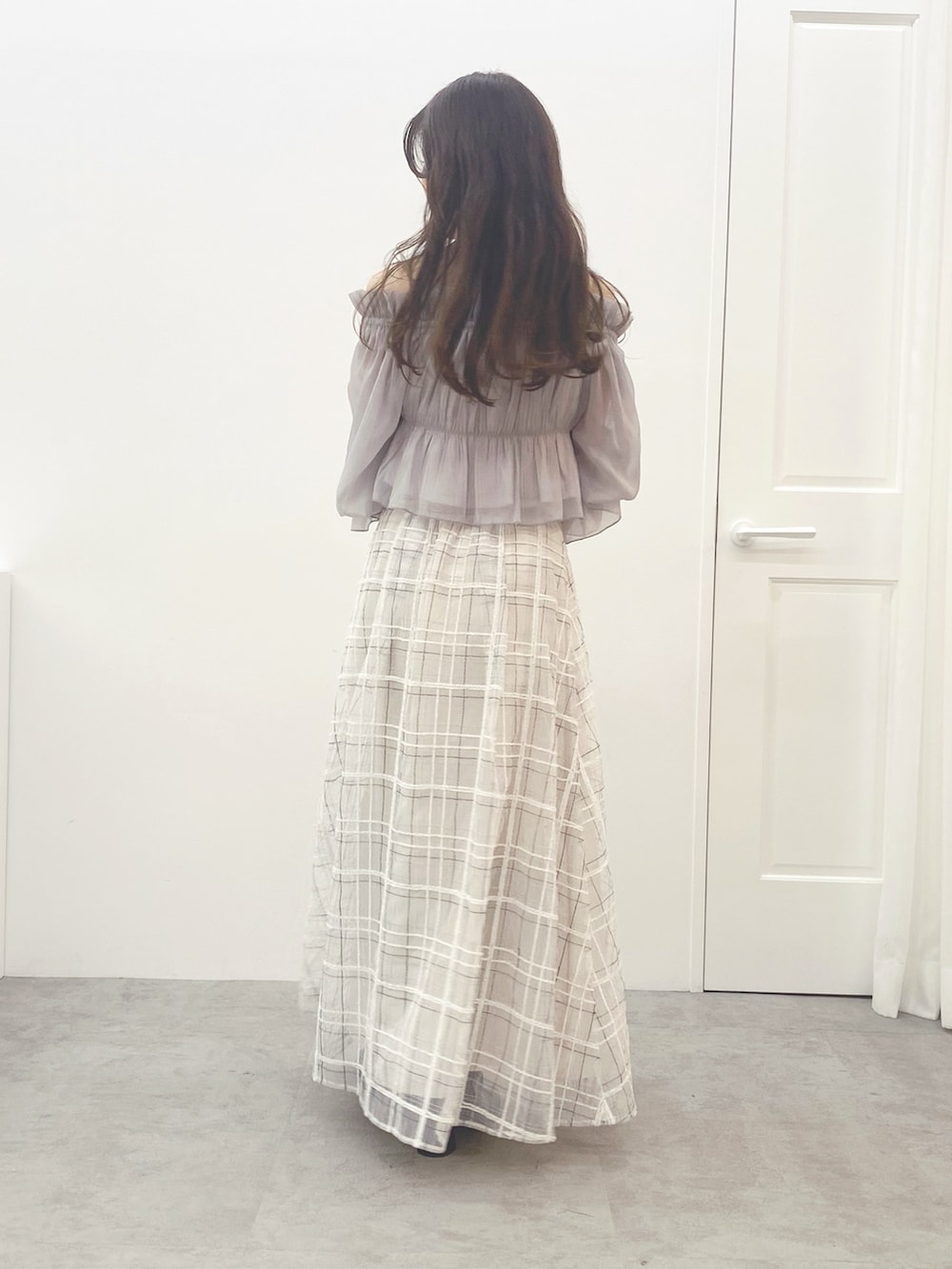 ホワイト系のハンドバッグ、ホワイト系のスカート、ブラック系のブーツを着用したレディースの夏コーディネートの6枚目の写真