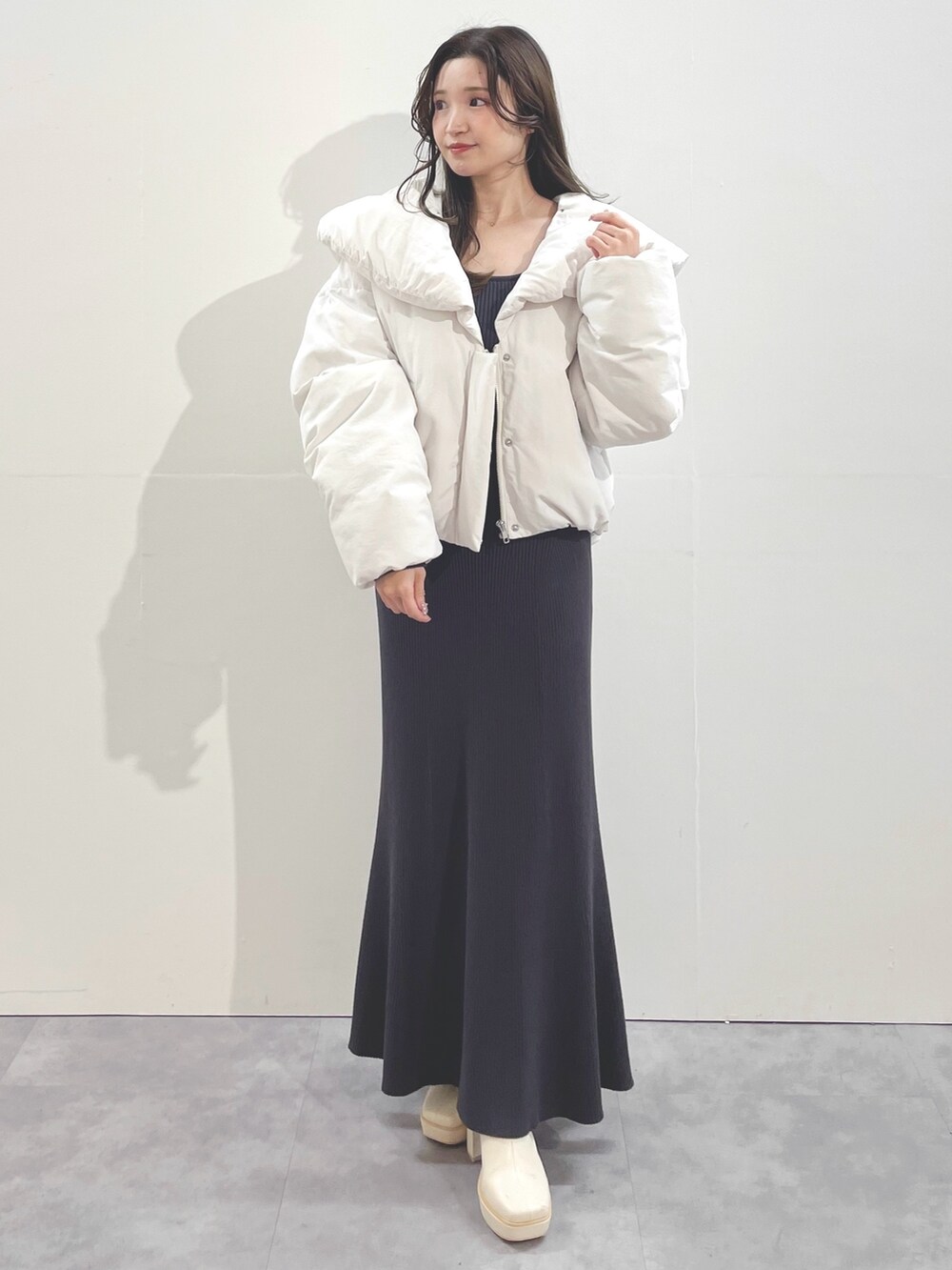 ホワイト系のブーツ、ホワイト系のダウンジャケット/コート、グレー系のワンピースを着用したレディースの冬コーディネートの2枚目の写真