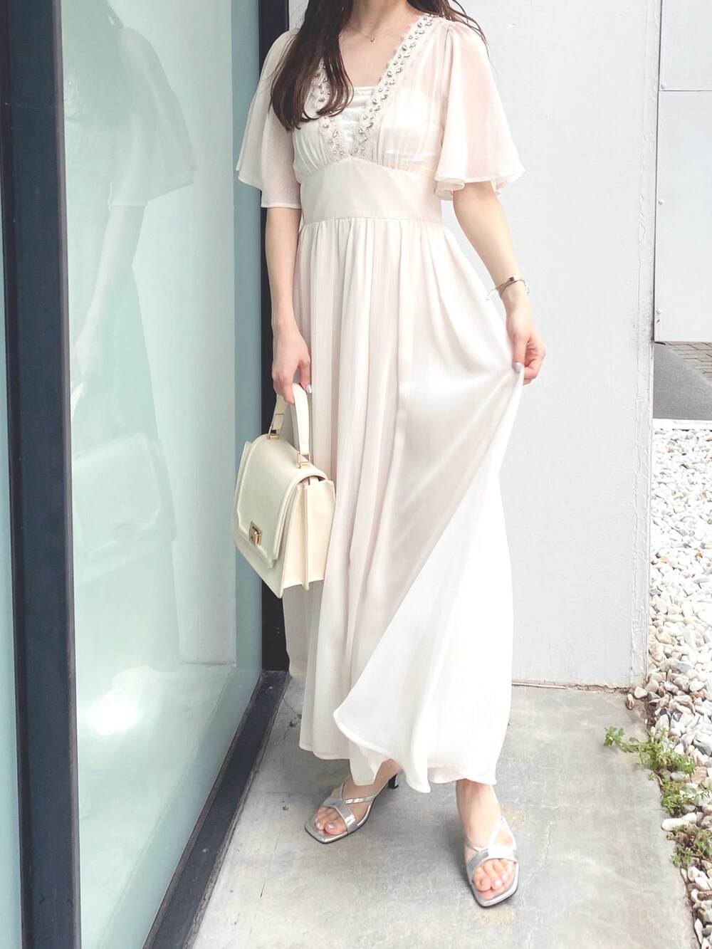 ホワイト系のハンドバッグ、ホワイト系のワンピース、シルバー系のサンダルを着用したレディースの夏コーディネートの3枚目の写真