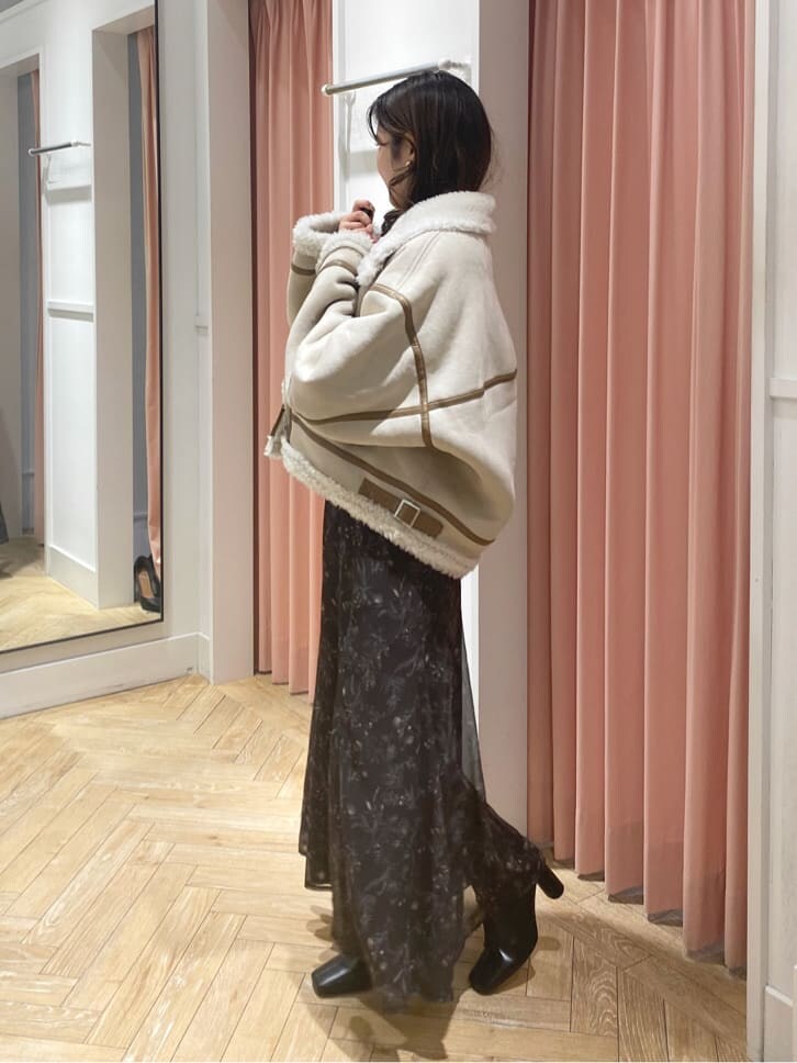 ベージュ系のムートンコート、ブラック系のブーツ、ホワイト系のニット/セーターを着用したレディースの秋コーディネートの5枚目の写真