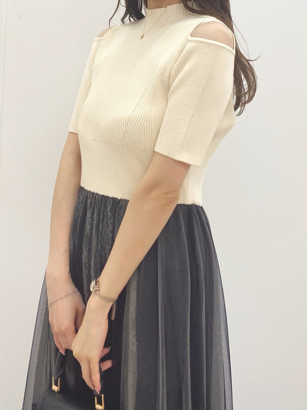 ブラック系のハンドバッグ、ブラック系のブーツ、ホワイト系のワンピースを着用したレディースの夏コーディネートの5枚目の写真