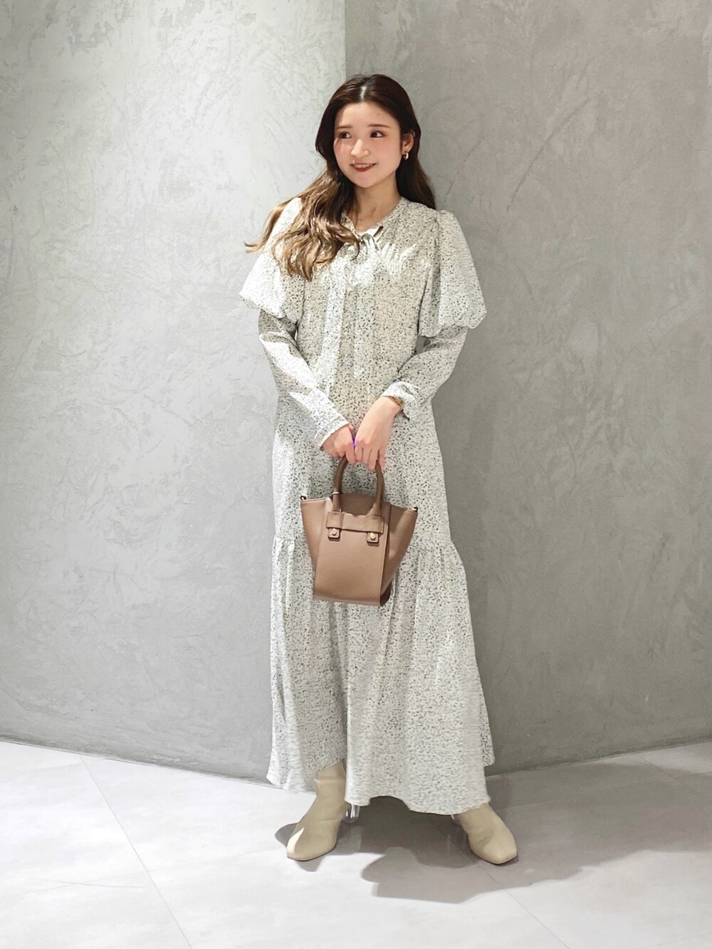 ホワイト系のワンピース、ホワイト系のブーツ、ブラウン系のハンドバッグを着用したレディースの冬コーディネートの4枚目の写真