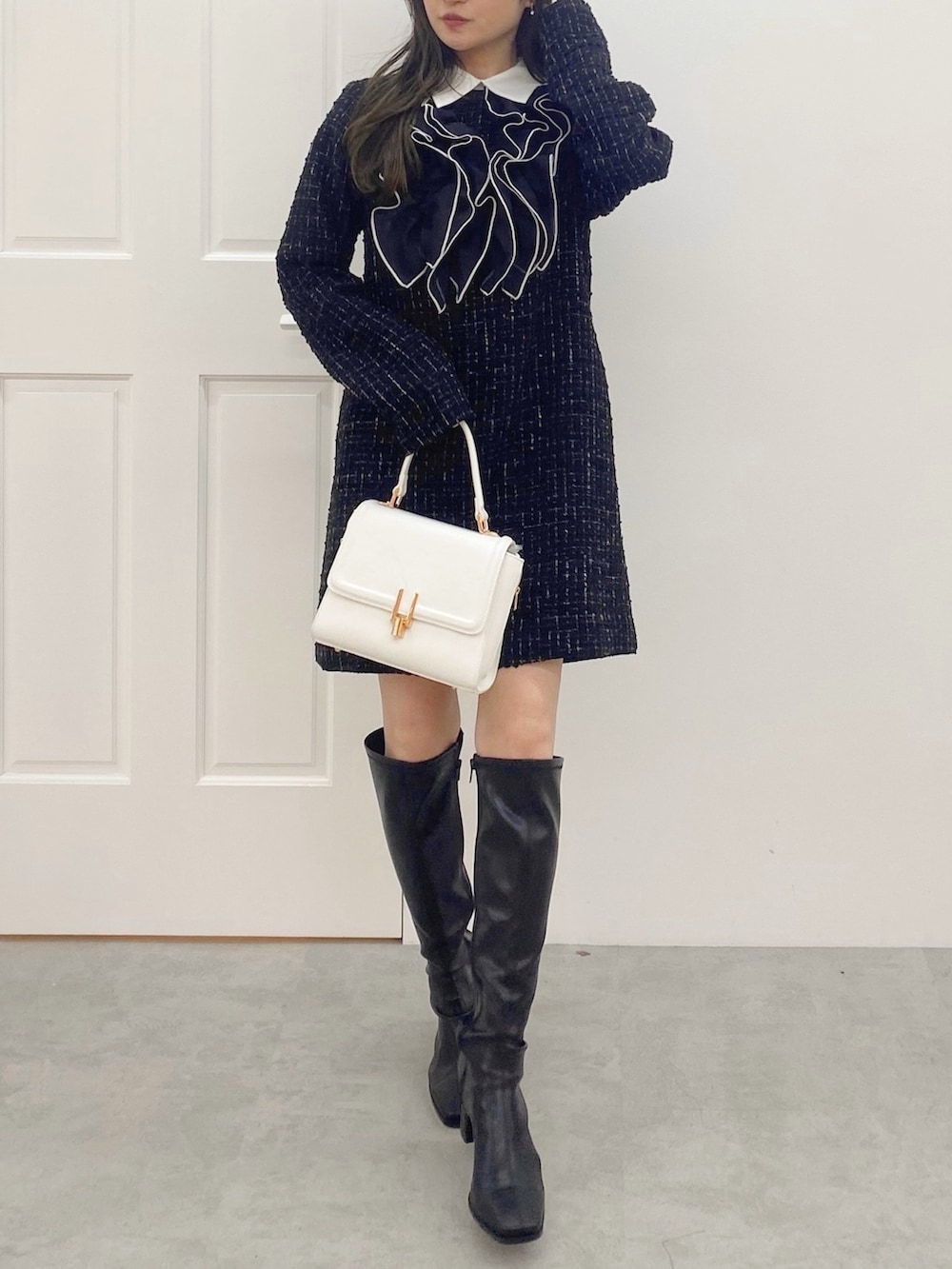 ブラック系のブーツ、ホワイト系のハンドバッグ、ブラック系のワンピースを着用したレディースの秋コーディネートの2枚目の写真