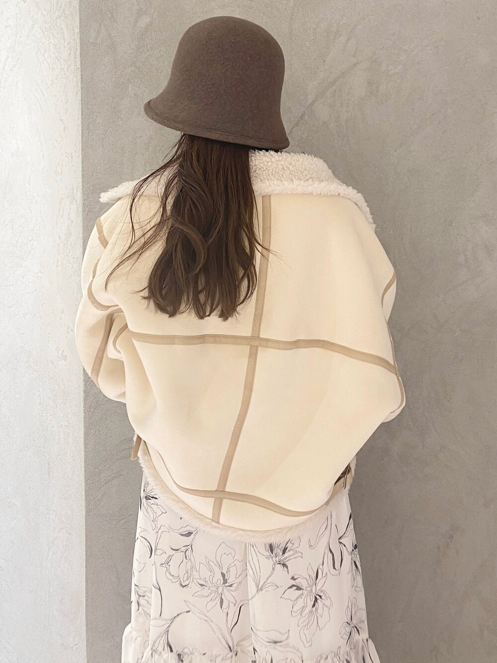 ホワイト系のムートンコート、ホワイト系のブーツ、ベージュ系のハンドバッグを着用したレディースの冬コーディネートの5枚目の写真