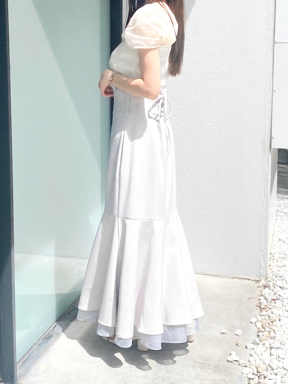 グレー系のスカート、ホワイト系のサンダル、ホワイト系のニット/セーターを着用したレディースの夏コーディネートの3枚目の写真