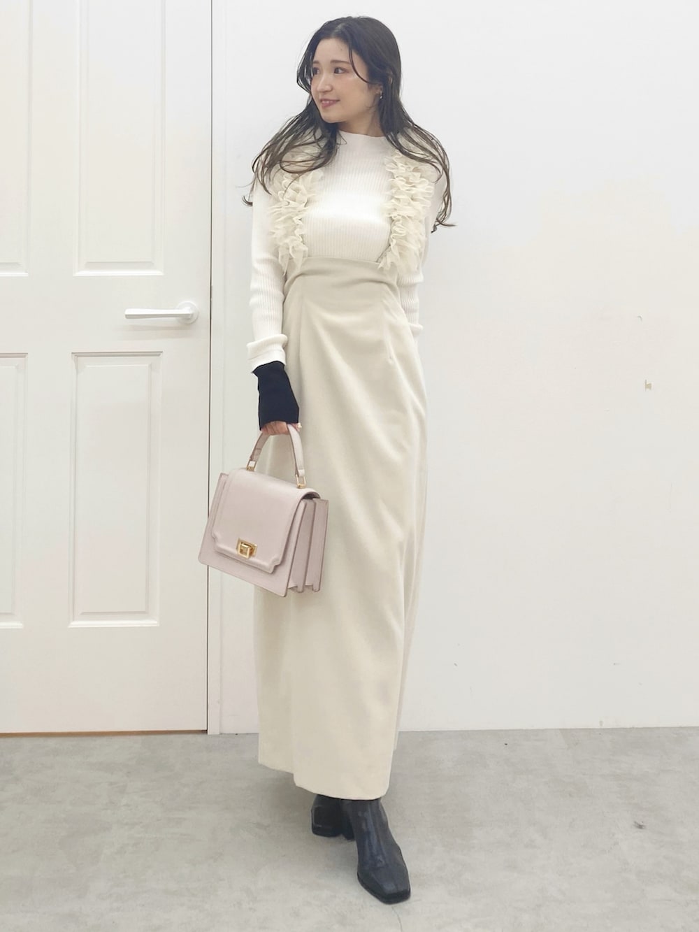 ピンク系のハンドバッグ、ブラック系のブーツ、ホワイト系のスカートを着用したレディースの秋コーディネートの2枚目の写真