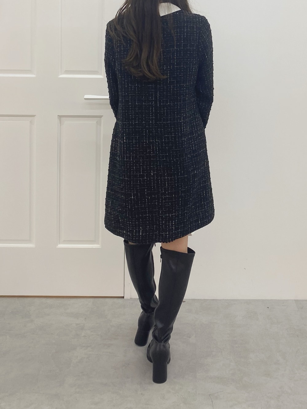 ブラック系のブーツ、ホワイト系のハンドバッグ、ブラック系のワンピースを着用したレディースの秋コーディネートの7枚目の写真