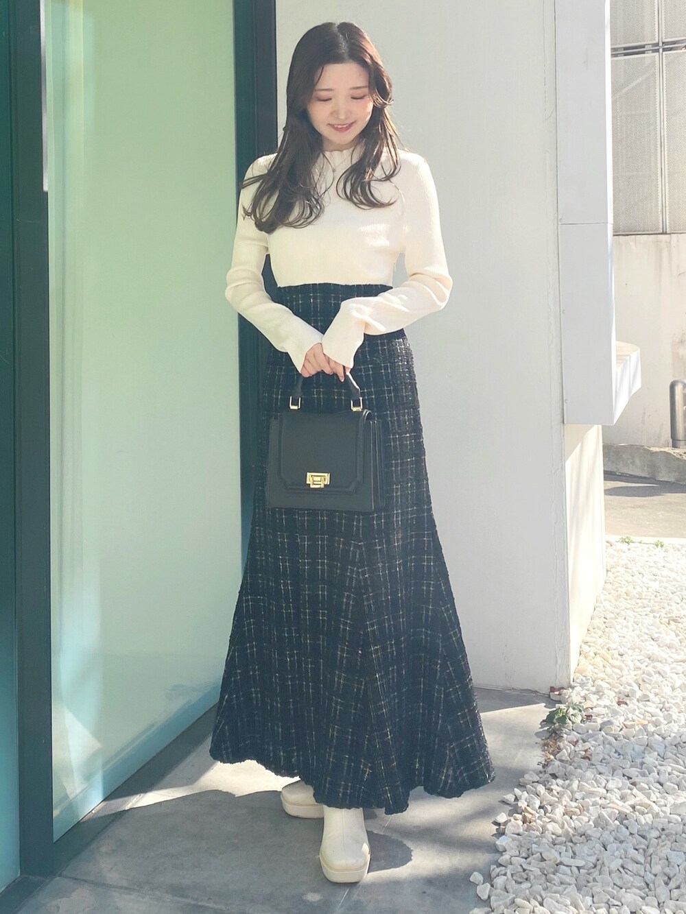 ホワイト系のブーツ、ブラック系のハンドバッグ、ブラック系のワンピースを着用したレディースの冬コーディネートの2枚目の写真