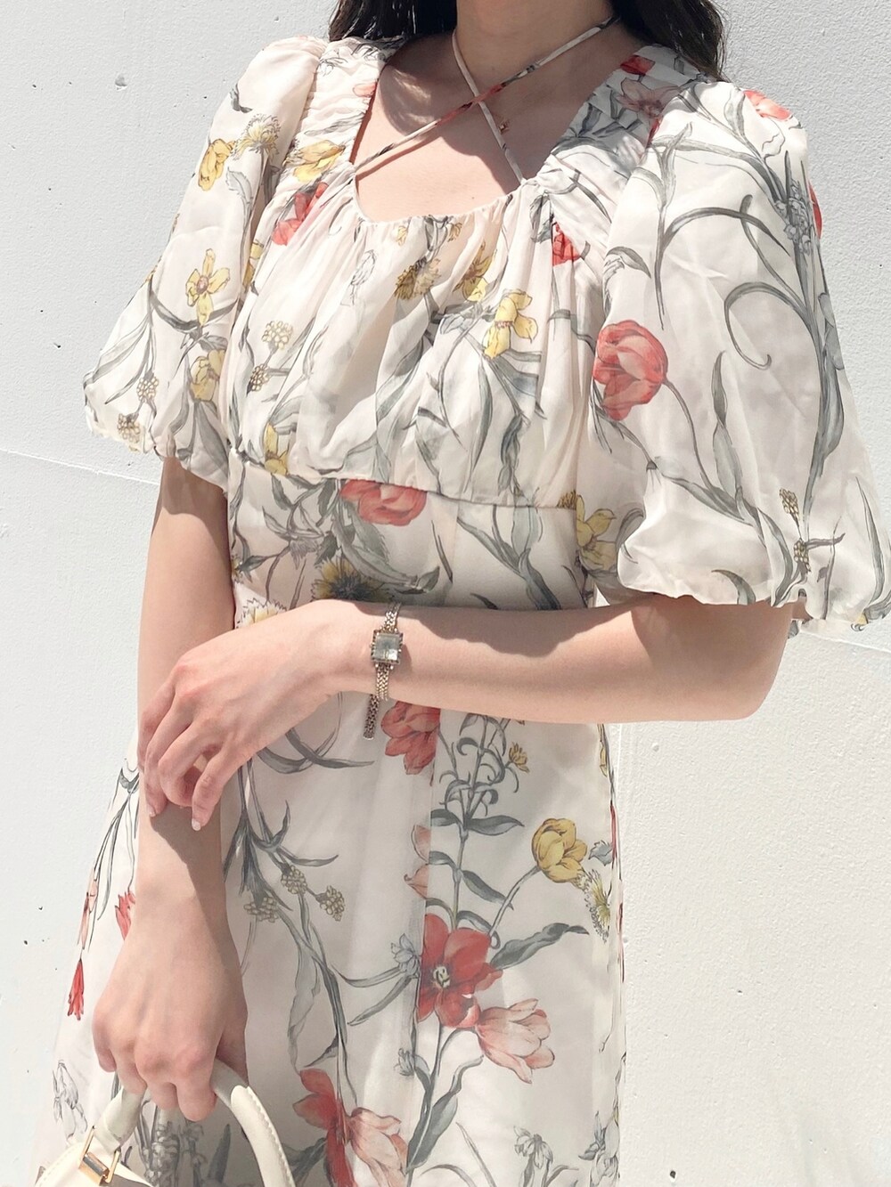 ホワイト系のハンドバッグ、ホワイト系のワンピース、ブラウン系のブーツを着用したレディースの夏コーディネートの2枚目の写真