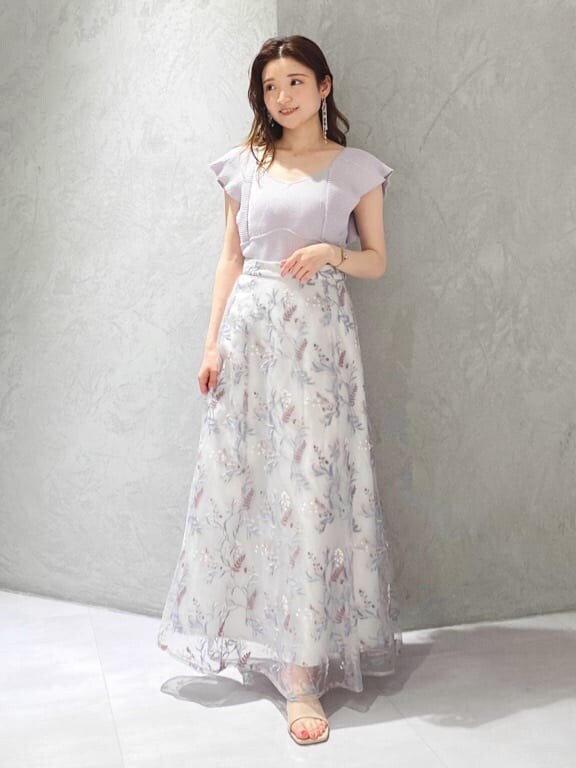 パープル系のニット/セーター、ブルー系のスカート、ベージュ系のサンダルを着用したレディースの春コーディネートの2枚目の写真