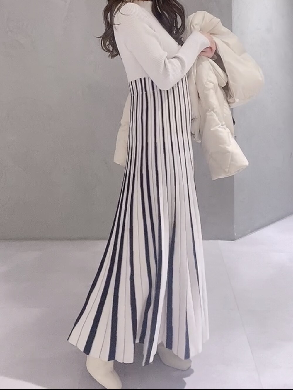 ホワイト系のワンピース、ホワイト系のブーツ、ブラウン系のハンドバッグを着用したレディースの冬コーディネートの7枚目の写真