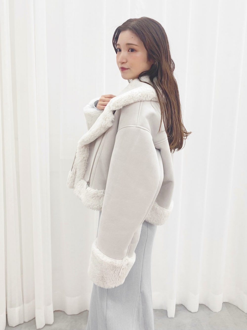 ブルー系のワンピース、ホワイト系のブーツ、グレー系のムートンコートを着用したレディースの秋コーディネートの2枚目の写真