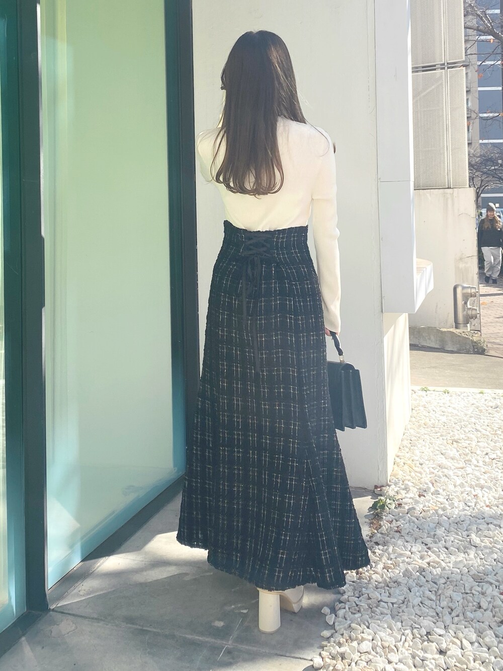 ホワイト系のブーツ、ブラック系のハンドバッグ、ブラック系のワンピースを着用したレディースの冬コーディネートの7枚目の写真