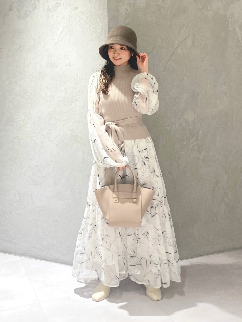 ホワイト系のワンピース、ベージュ系のハンドバッグ、ホワイト系のブーツを着用したレディースの冬コーディネートの2枚目の写真