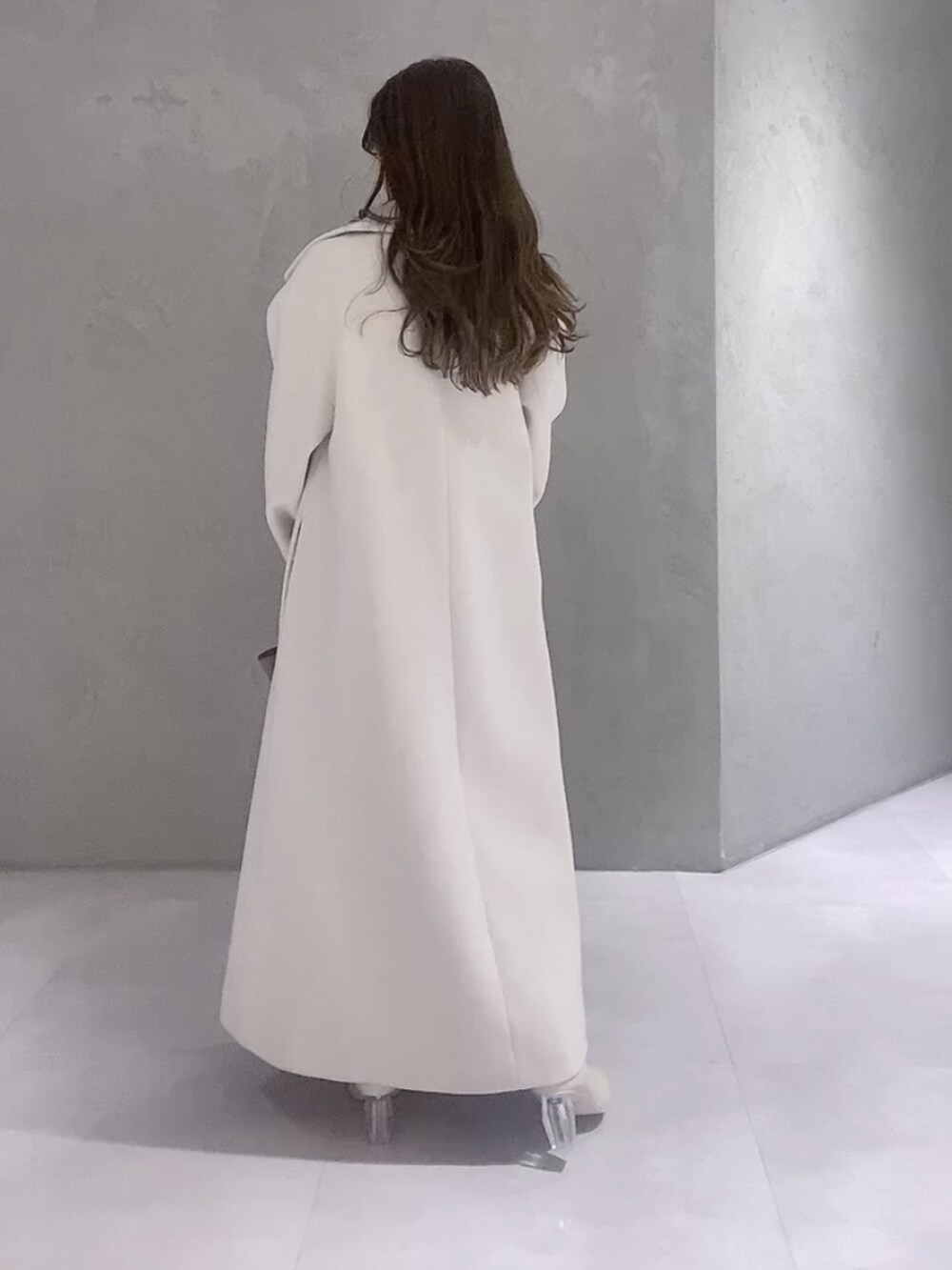 ホワイト系のニット/セーター、ホワイト系のチェスターコート、ブラウン系のハンドバッグを着用したレディースの冬コーディネートの4枚目の写真