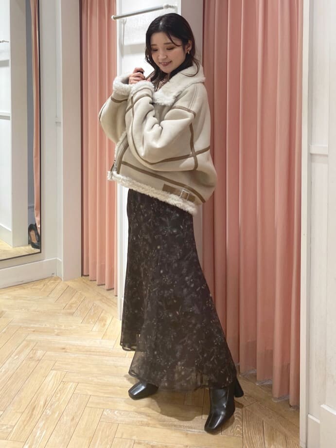 ベージュ系のムートンコート、ブラック系のブーツ、ホワイト系のニット/セーターを着用したレディースの秋コーディネートの3枚目の写真