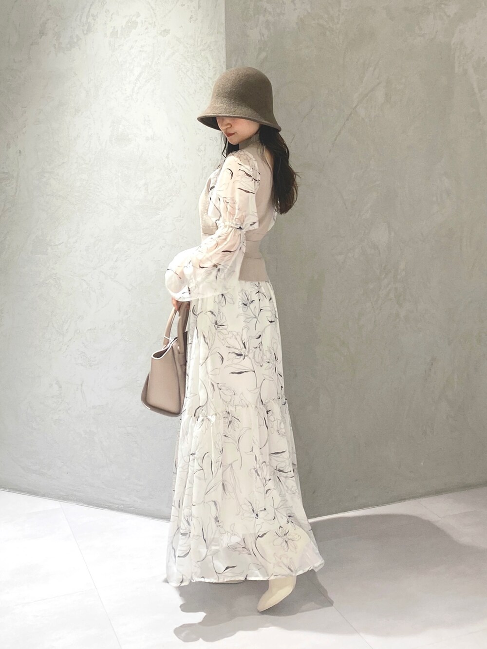 ホワイト系のワンピース、ベージュ系のハンドバッグ、ホワイト系のブーツを着用したレディースの冬コーディネートの9枚目の写真