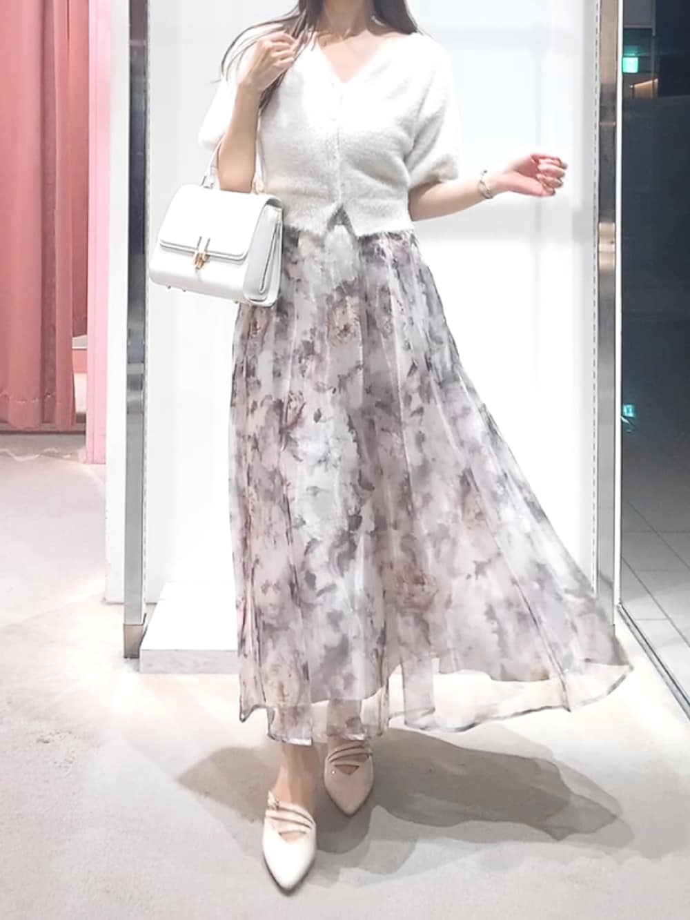 ベージュ系のパンプス、ホワイト系のハンドバッグ、ホワイト系のカーディガン/ボレロを着用したレディースの夏コーディネートの2枚目の写真