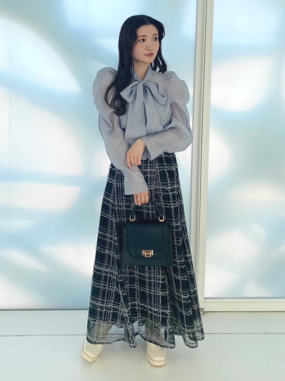 ブラック系のハンドバッグ、ホワイト系のブーツ、ブラック系のスカートを着用したレディースの秋コーディネートの3枚目の写真