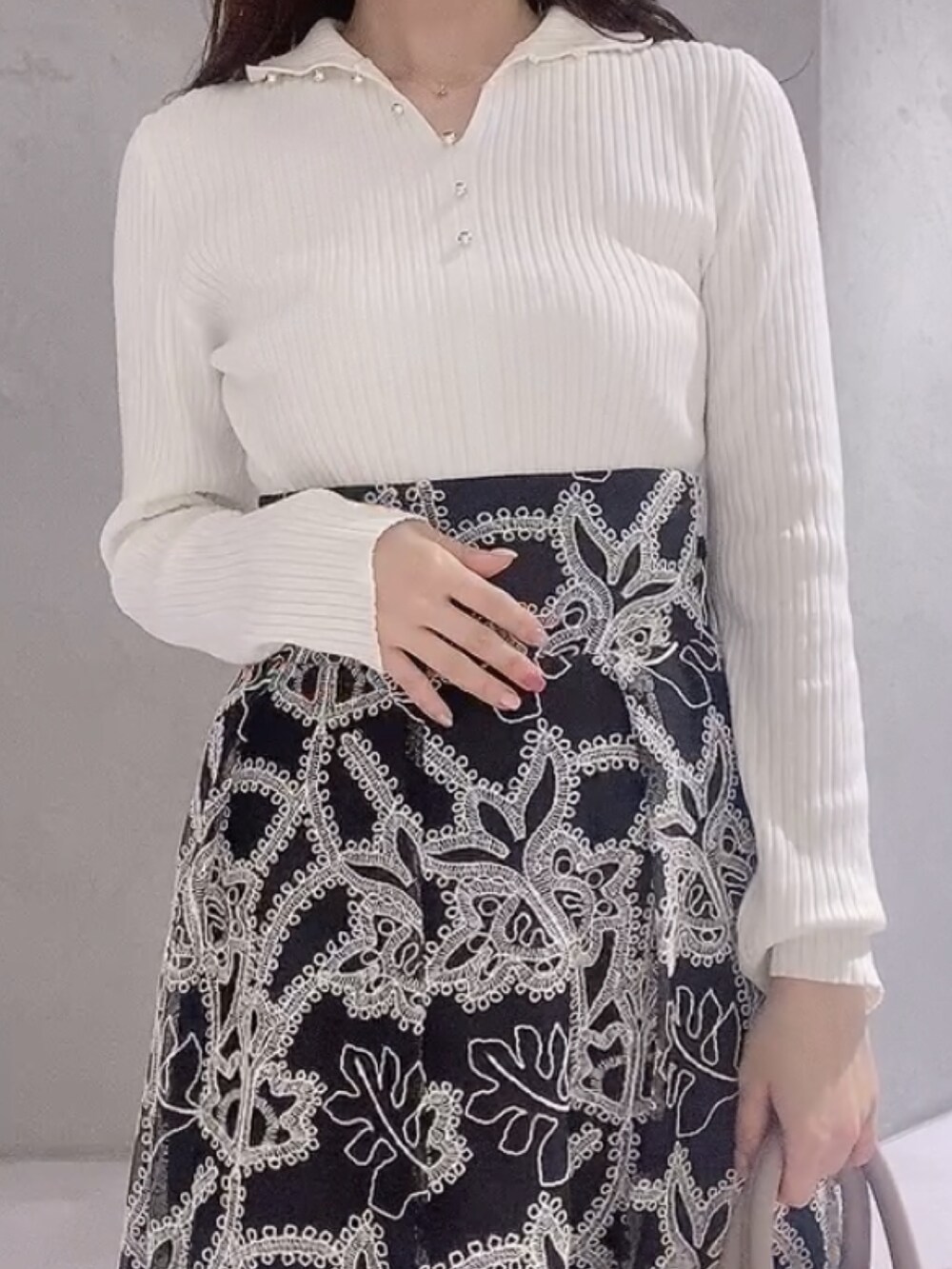 ベージュ系のハンドバッグ、ブラック系のスカート、ホワイト系のニット/セーターを着用したレディースの冬コーディネートの7枚目の写真