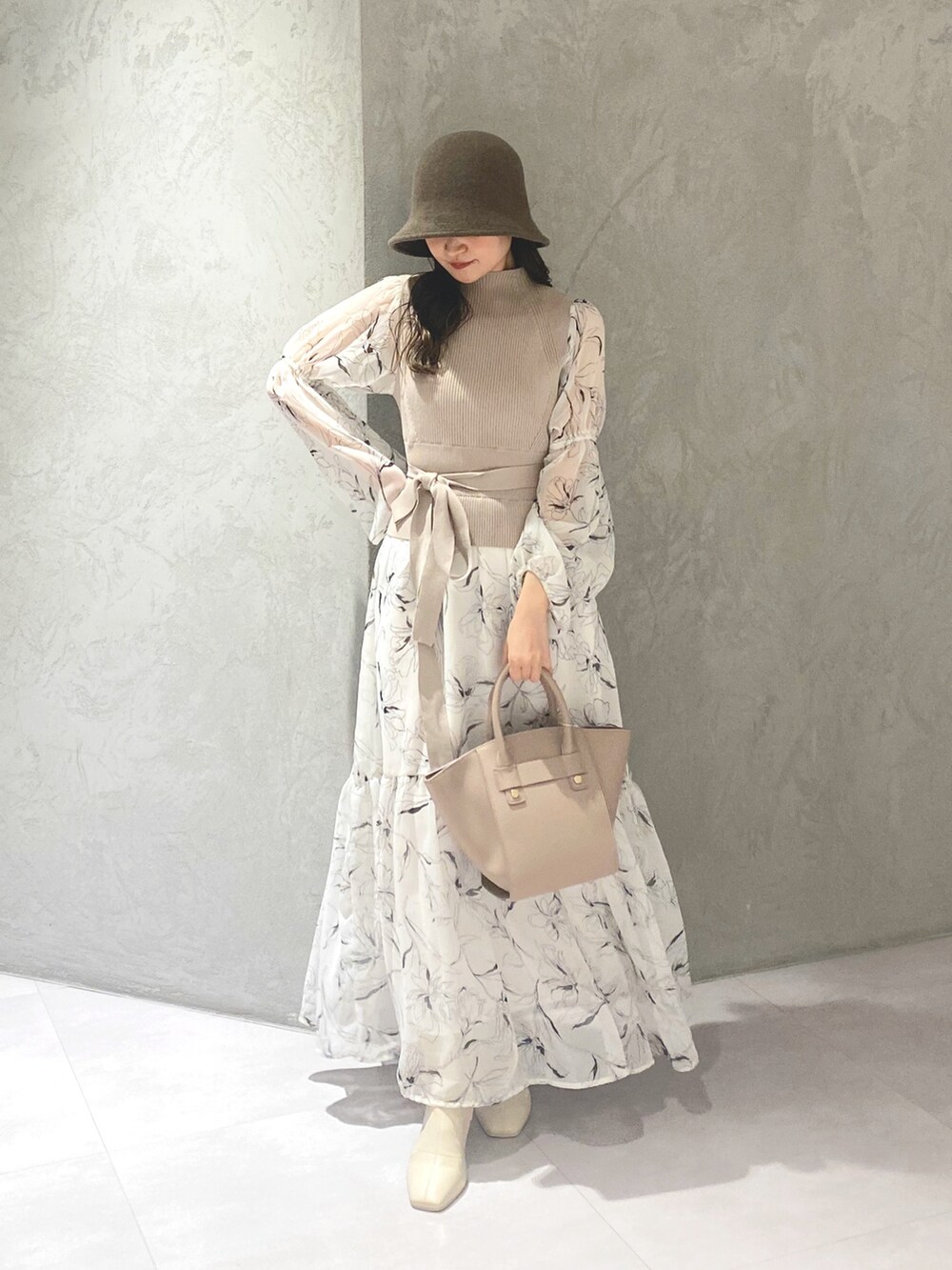 ホワイト系のワンピース、ベージュ系のハンドバッグ、ホワイト系のブーツを着用したレディースの冬コーディネートの3枚目の写真