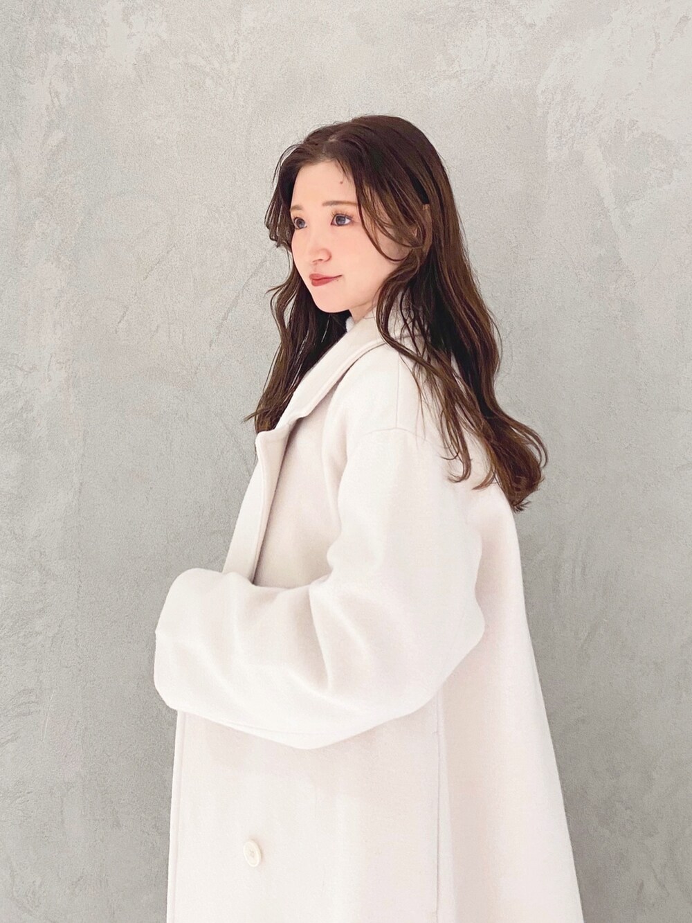 ホワイト系のチェスターコート、ホワイト系のブーツ、パープル系のニット/セーターを着用したレディースの冬コーディネートの5枚目の写真