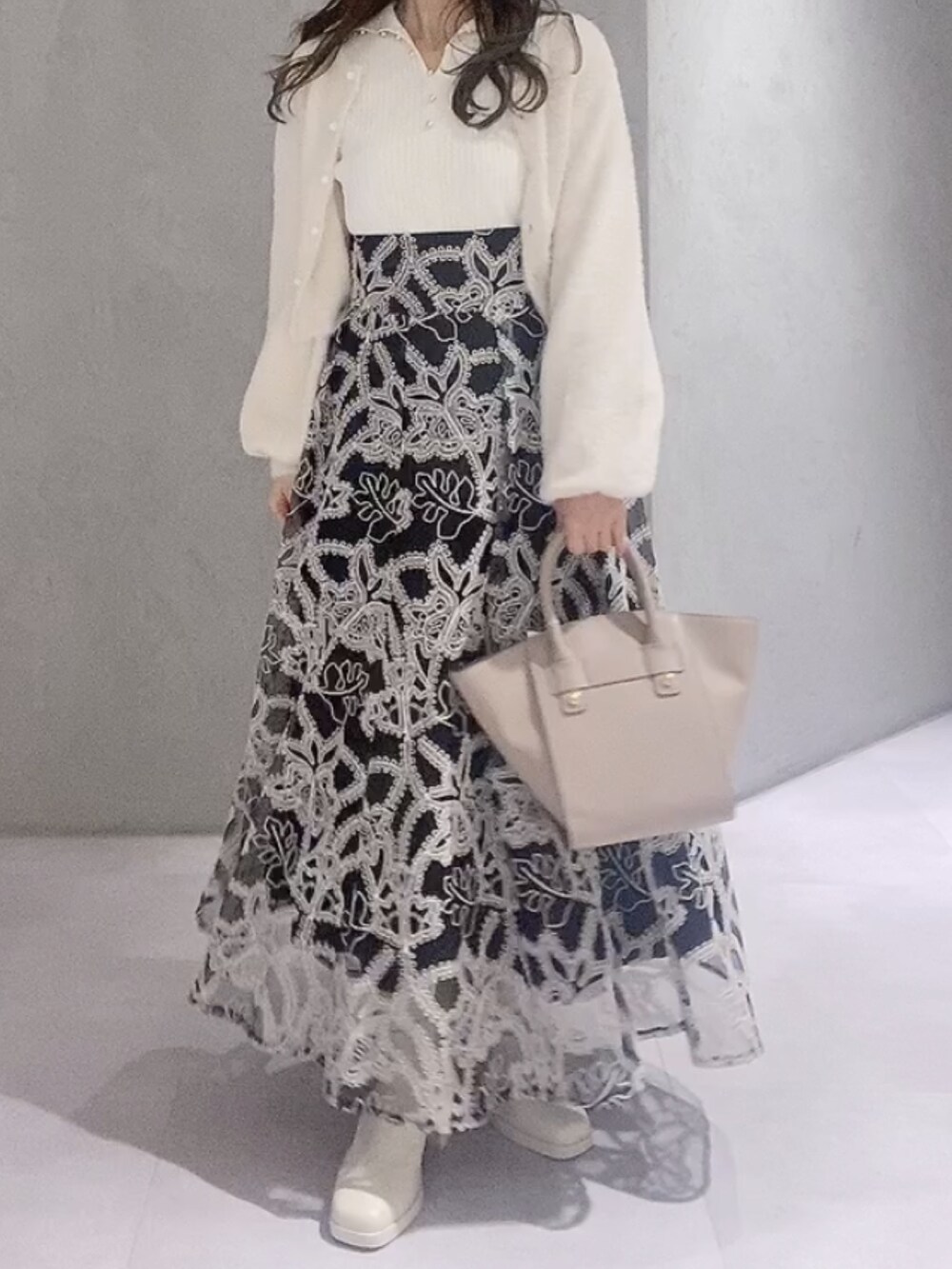 ベージュ系のハンドバッグ、ブラック系のスカート、ホワイト系のニット/セーターを着用したレディースの冬コーディネートの6枚目の写真