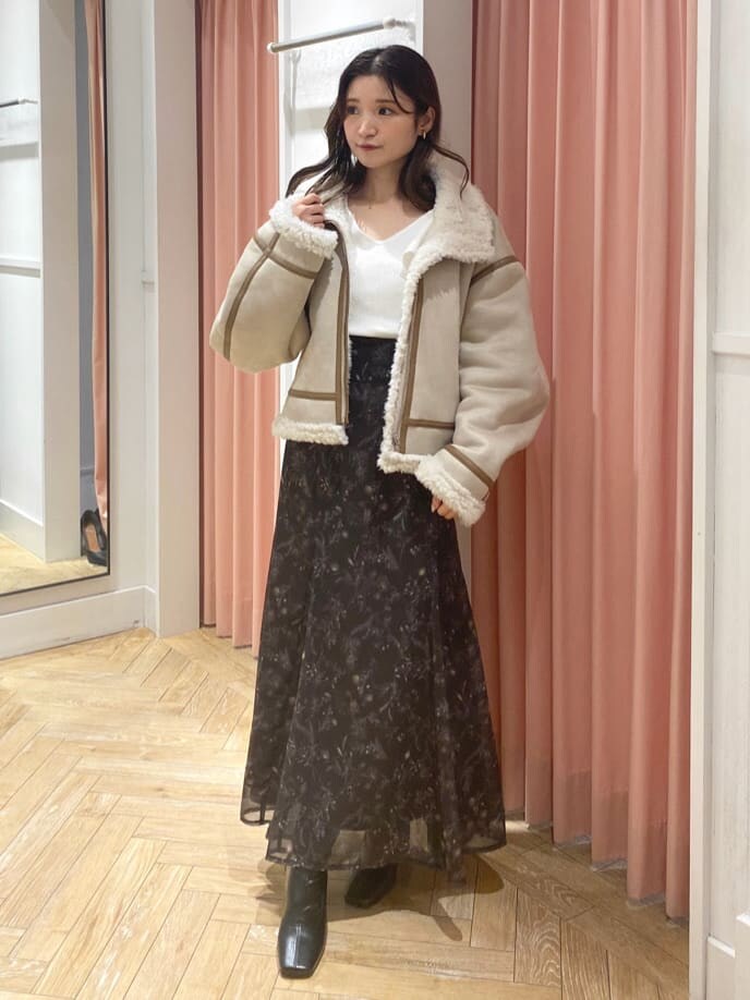 ベージュ系のムートンコート、ブラック系のブーツ、ホワイト系のニット/セーターを着用したレディースの秋コーディネートの2枚目の写真