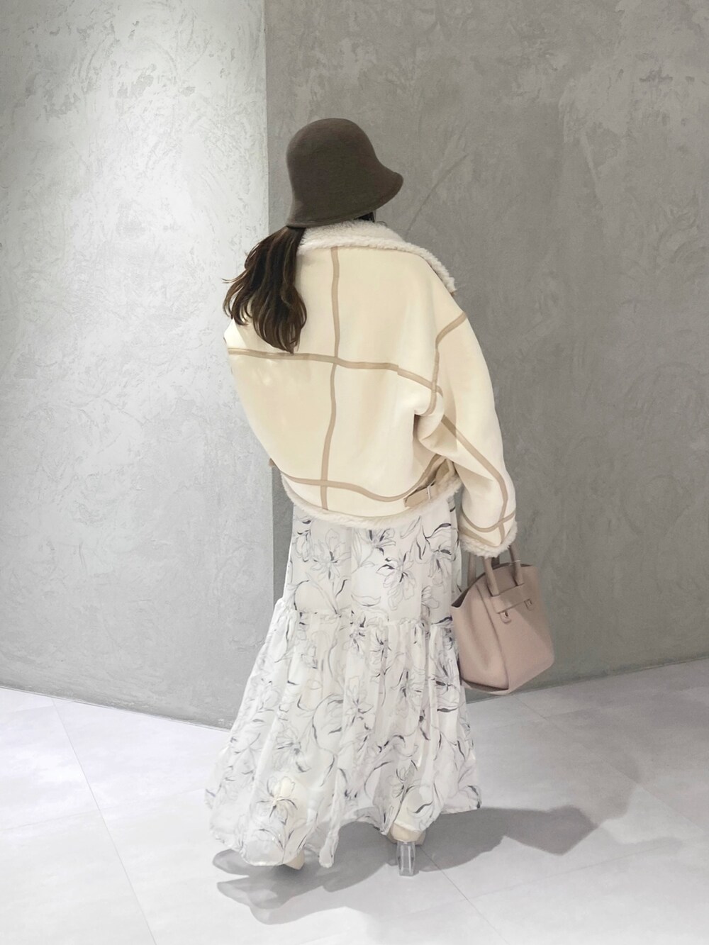 ホワイト系のムートンコート、ホワイト系のブーツ、ベージュ系のハンドバッグを着用したレディースの冬コーディネートの7枚目の写真