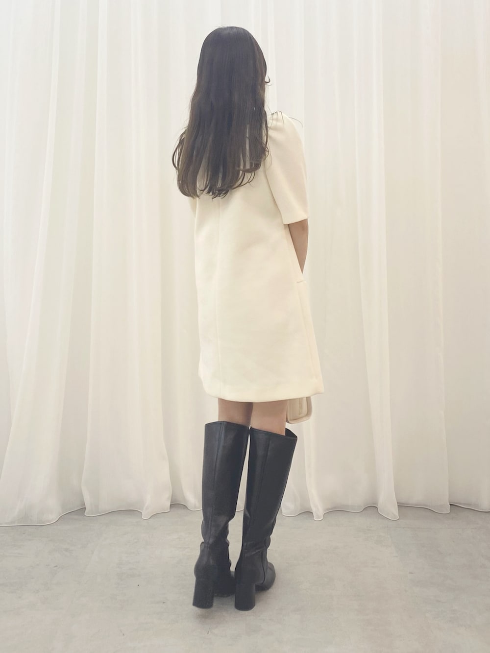 ホワイト系のハンドバッグ、ホワイト系のワンピース、ブラック系のブーツを着用したレディースの夏コーディネートの7枚目の写真