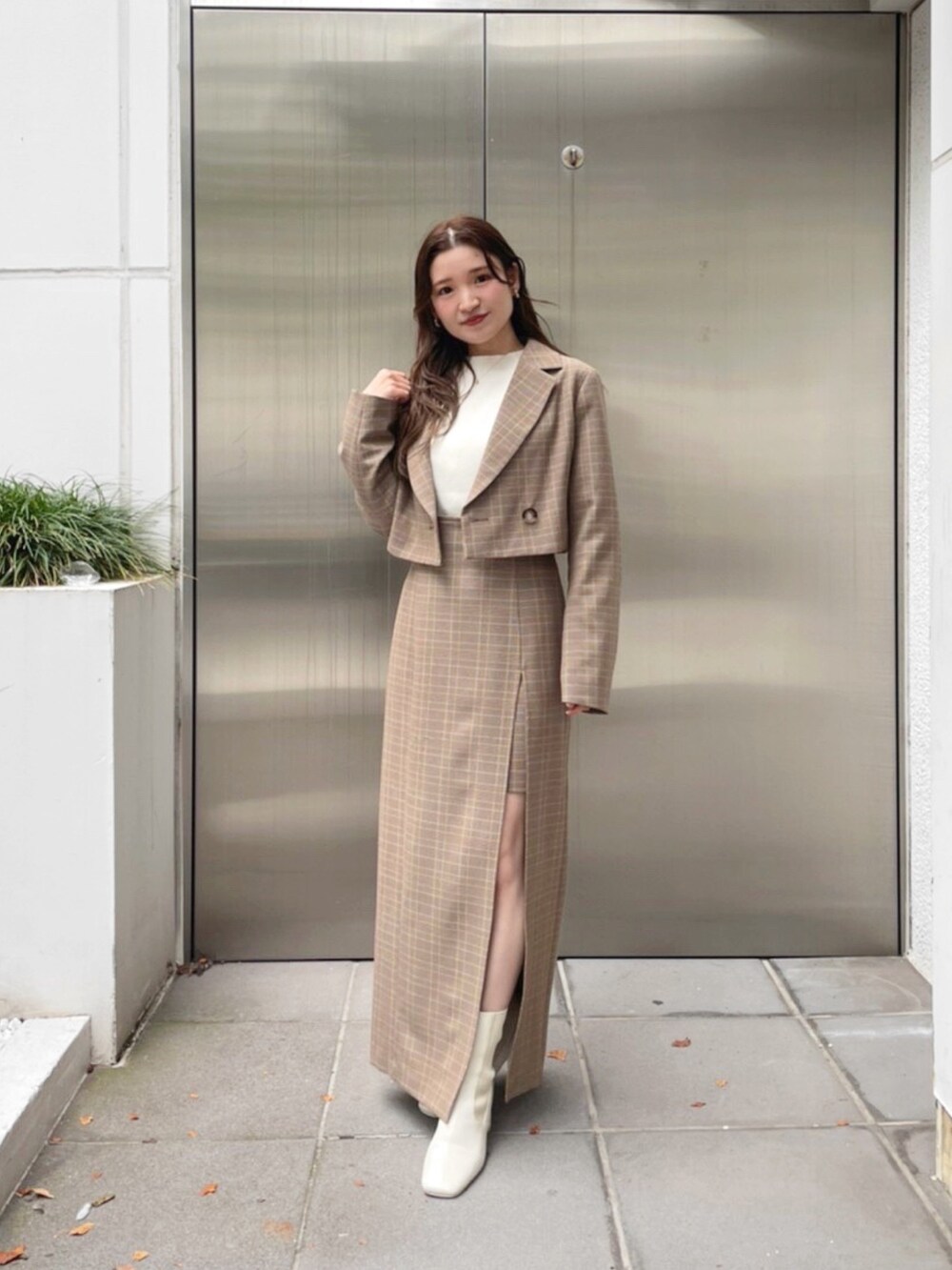 ベージュ系のテーラードジャケット、ベージュ系のスカート、ホワイト系のブーツを着用したレディースの秋コーディネートの3枚目の写真