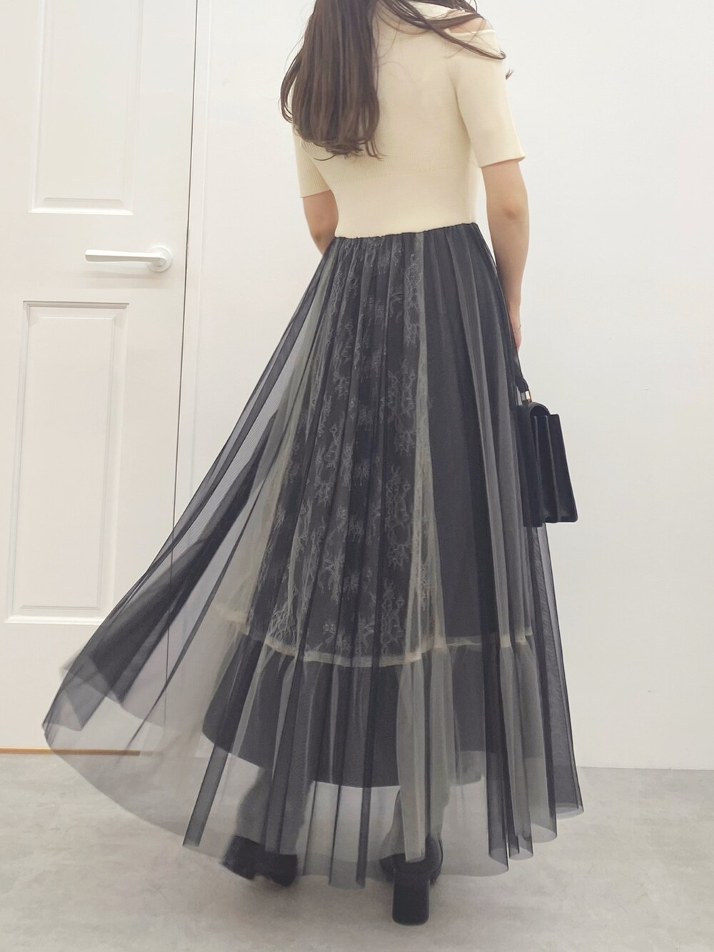 ブラック系のハンドバッグ、ブラック系のブーツ、ホワイト系のワンピースを着用したレディースの夏コーディネートの7枚目の写真