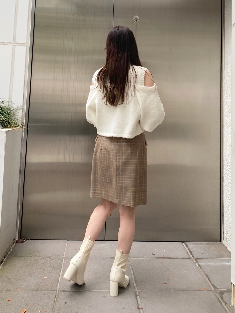 ホワイト系のニット/セーター、ベージュ系のスカート、ホワイト系のブーツを着用したレディースの秋コーディネートの7枚目の写真