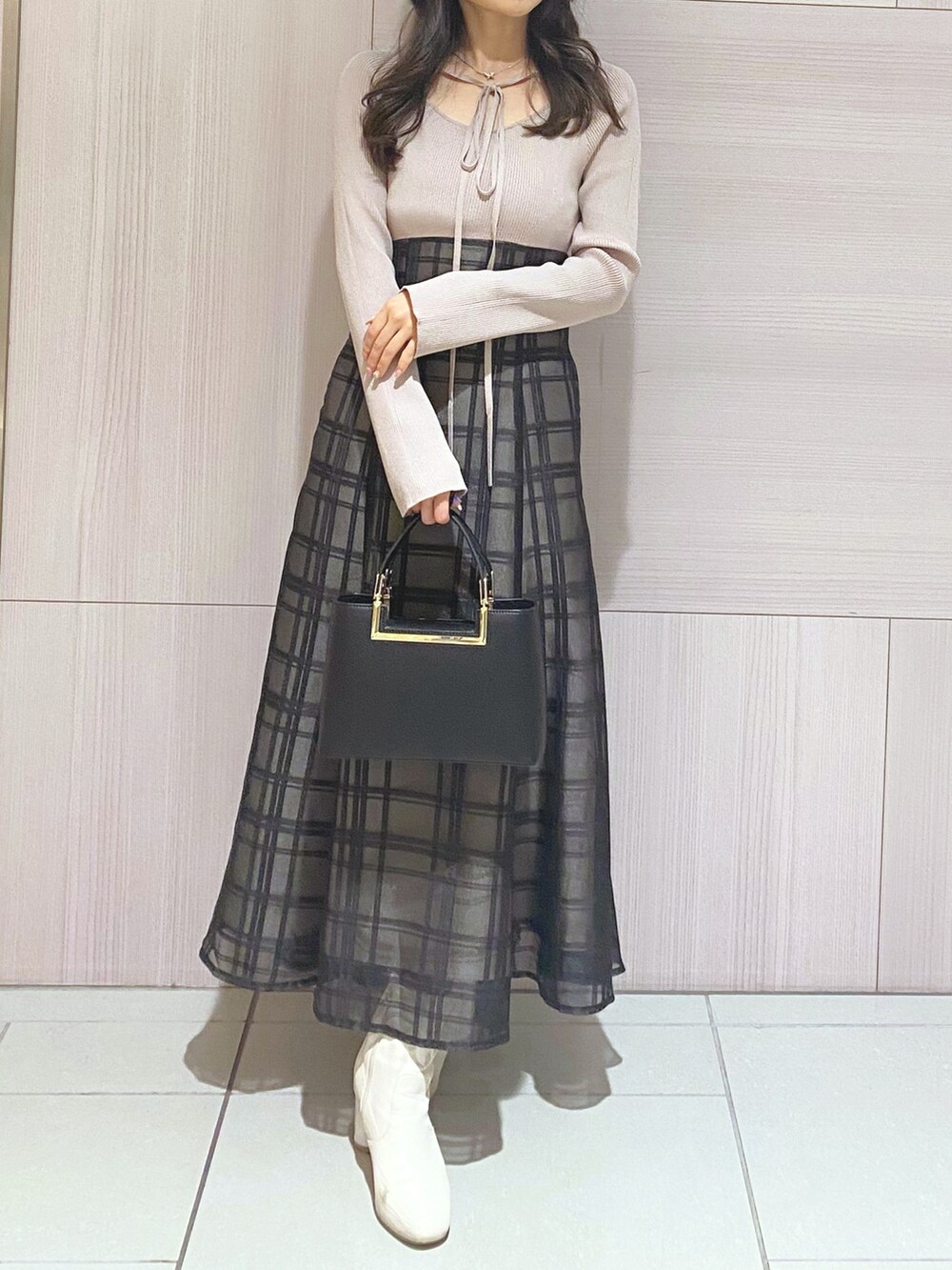 ピンク系のワンピース、ブラック系のハンドバッグ、ホワイト系のブーツを着用したレディースの秋コーディネートの4枚目の写真
