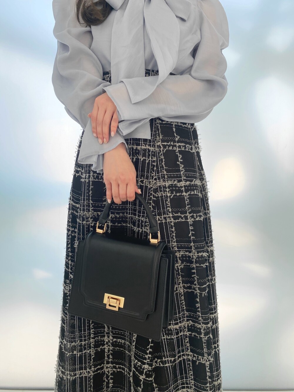 ブラック系のハンドバッグ、ホワイト系のブーツ、ブラック系のスカートを着用したレディースの秋コーディネートの5枚目の写真