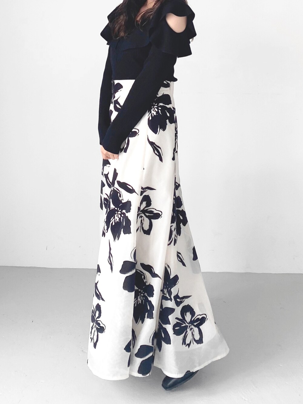 ブラック系のブーツ、ホワイト系のスカート、ブラック系のニット/セーターを着用したレディースの秋コーディネートの3枚目の写真