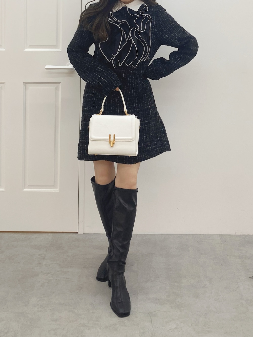 ブラック系のブーツ、ホワイト系のハンドバッグ、ブラック系のワンピースを着用したレディースの秋コーディネートの3枚目の写真