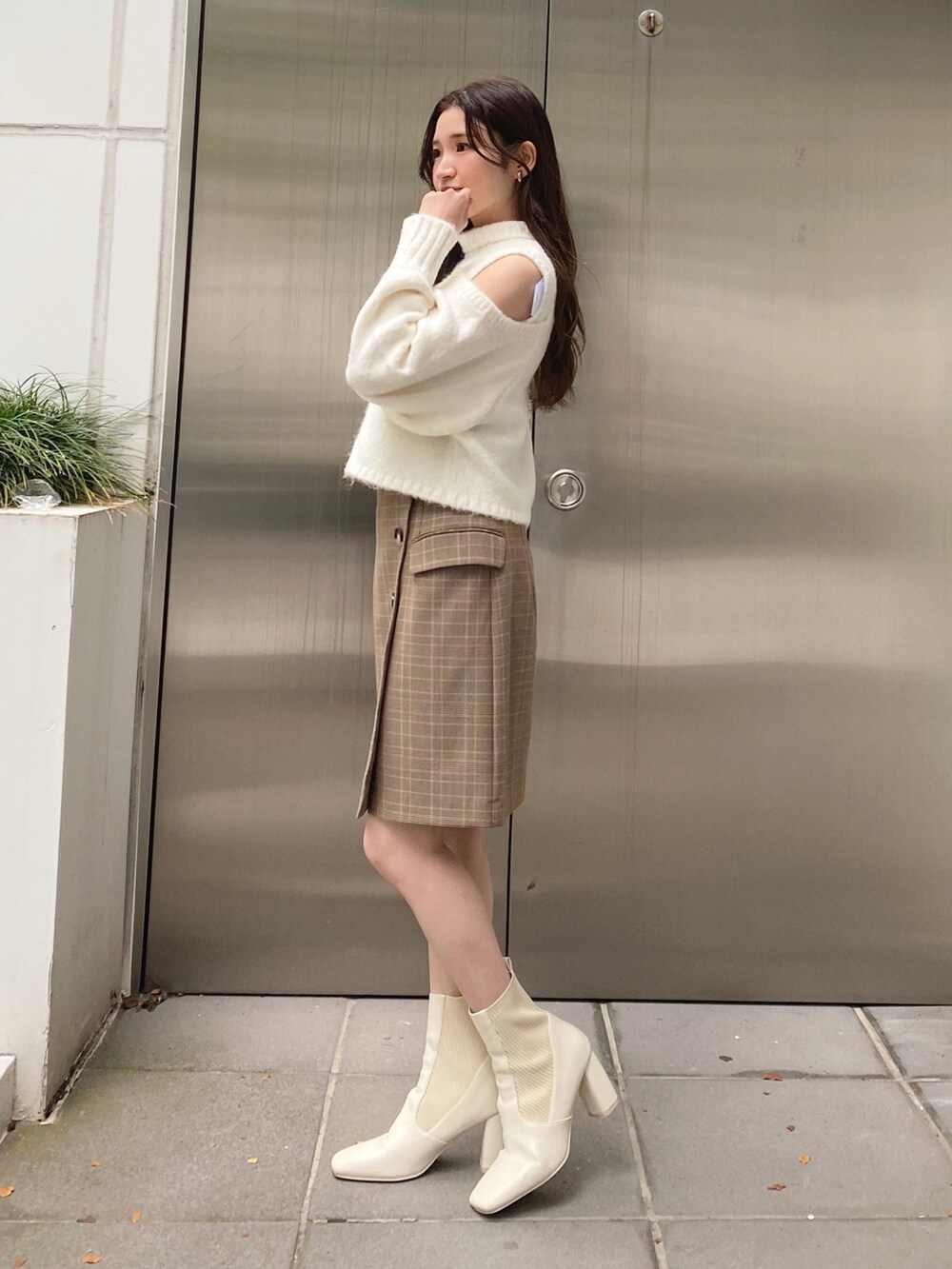 ホワイト系のニット/セーター、ベージュ系のスカート、ホワイト系のブーツを着用したレディースの秋コーディネートの3枚目の写真