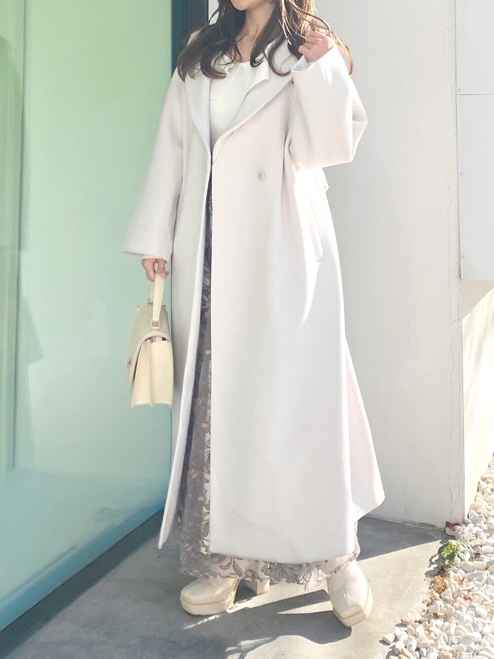 ホワイト系のブーツ、ホワイト系のハンドバッグ、ホワイト系のチェスターコートを着用したレディースの冬コーディネートの2枚目の写真
