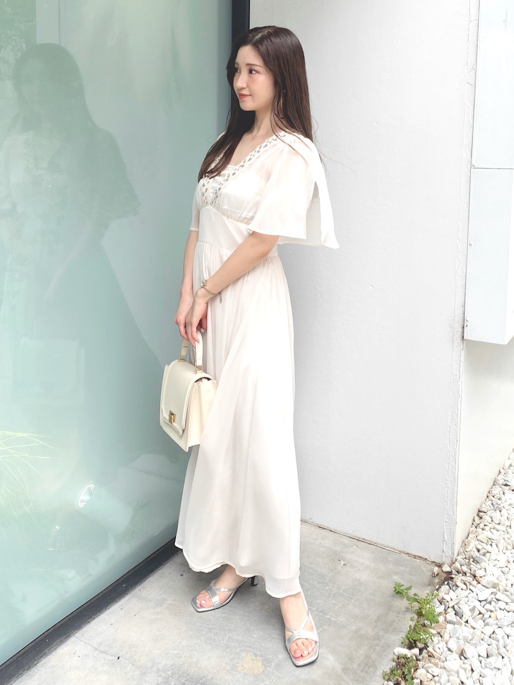 ホワイト系のハンドバッグ、ホワイト系のワンピース、シルバー系のサンダルを着用したレディースの夏コーディネートの2枚目の写真