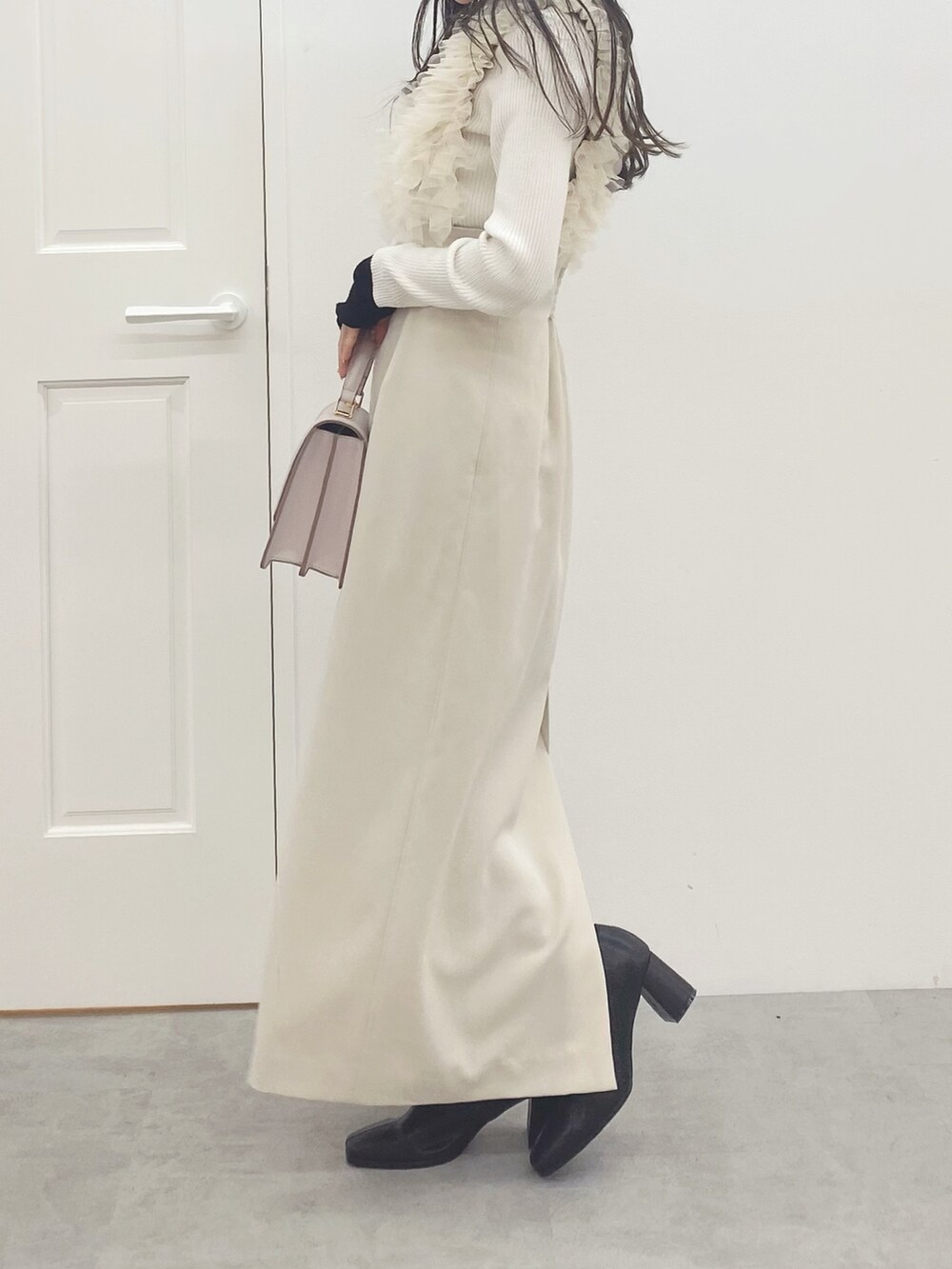 ピンク系のハンドバッグ、ブラック系のブーツ、ホワイト系のスカートを着用したレディースの秋コーディネートの6枚目の写真