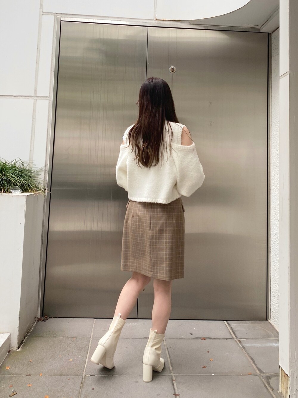 ホワイト系のニット/セーター、ベージュ系のスカート、ホワイト系のブーツを着用したレディースの秋コーディネートの9枚目の写真