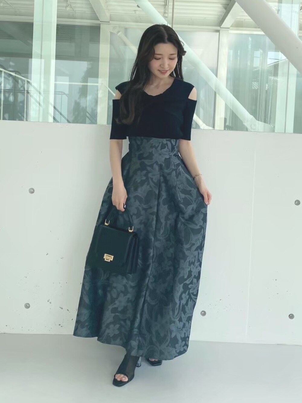 ブラック系のハンドバッグ、ブラック系のブーツ、ブラック系のニット/セーターを着用したレディースの秋コーディネートの2枚目の写真