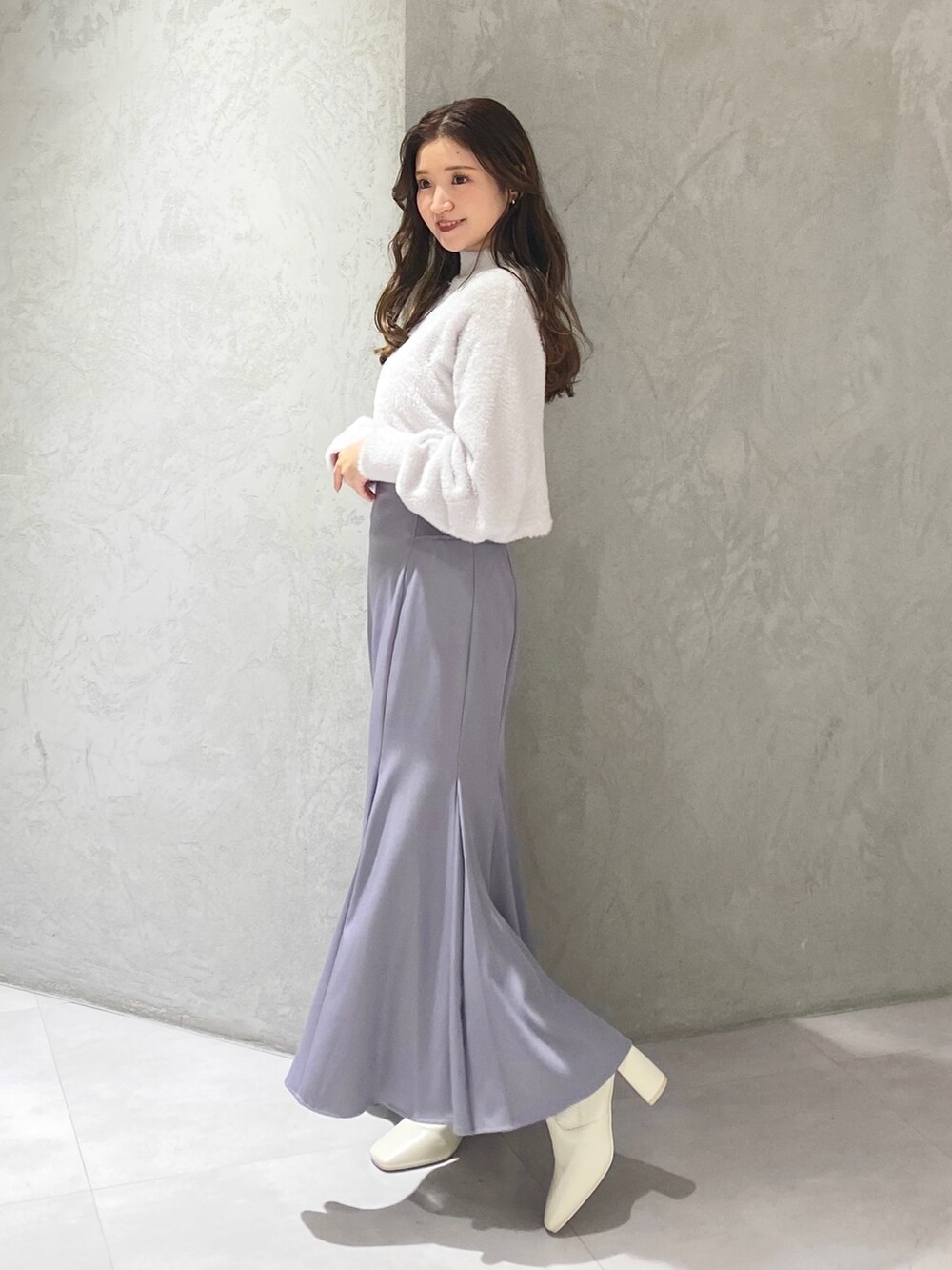 ホワイト系のブーツ、ブルー系のスカート、パープル系のニット/セーターを着用したレディースの秋コーディネートの3枚目の写真