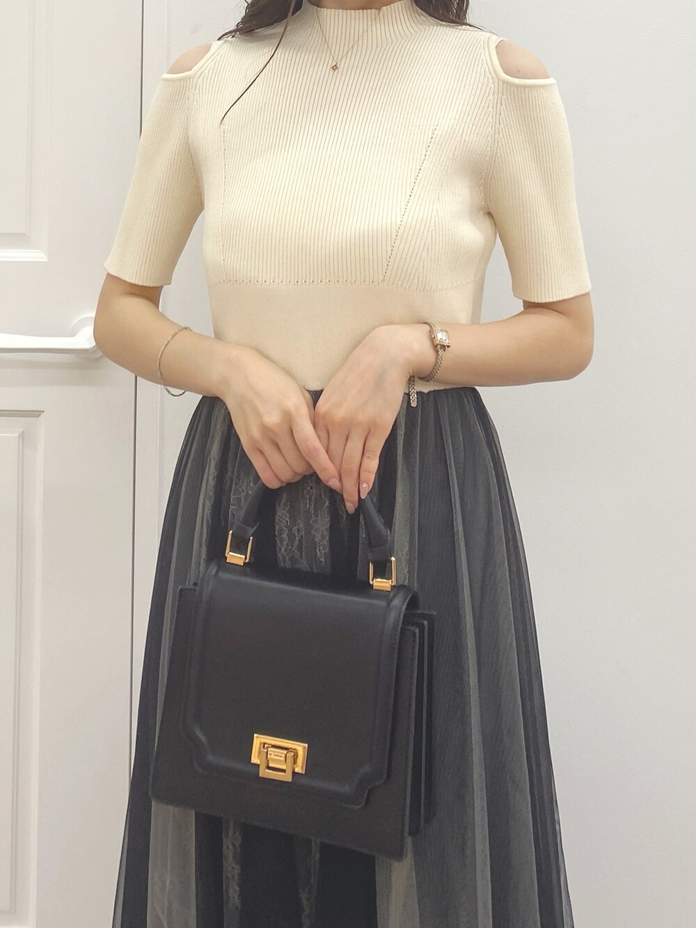 ブラック系のハンドバッグ、ブラック系のブーツ、ホワイト系のワンピースを着用したレディースの夏コーディネートの6枚目の写真