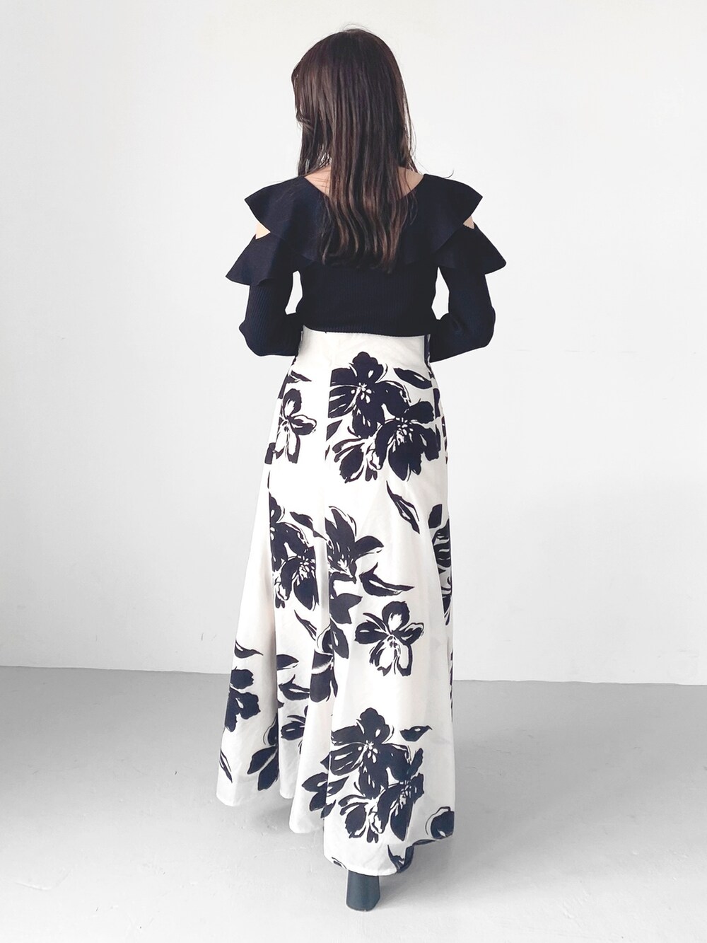 ブラック系のブーツ、ホワイト系のスカート、ブラック系のニット/セーターを着用したレディースの秋コーディネートの6枚目の写真