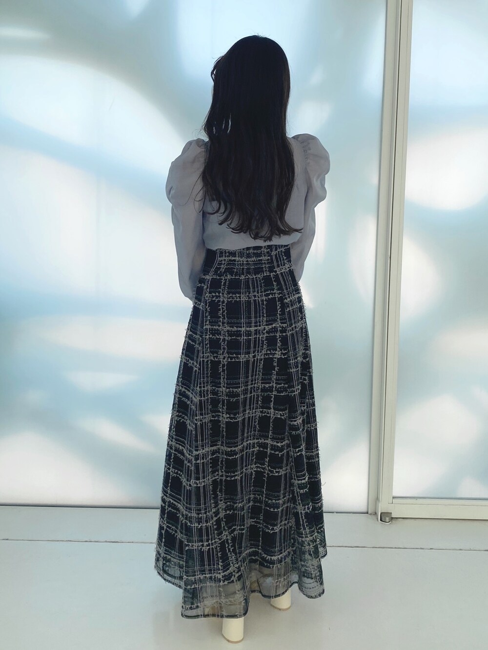 ブラック系のハンドバッグ、ホワイト系のブーツ、ブラック系のスカートを着用したレディースの秋コーディネートの6枚目の写真